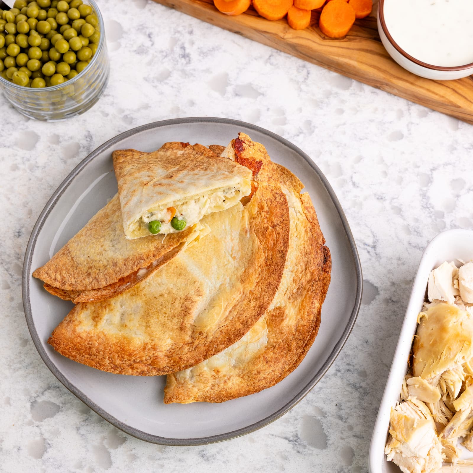 Rise & Puff Chicken Pot Pie on a plate surrounded by the ingredients it is made with.