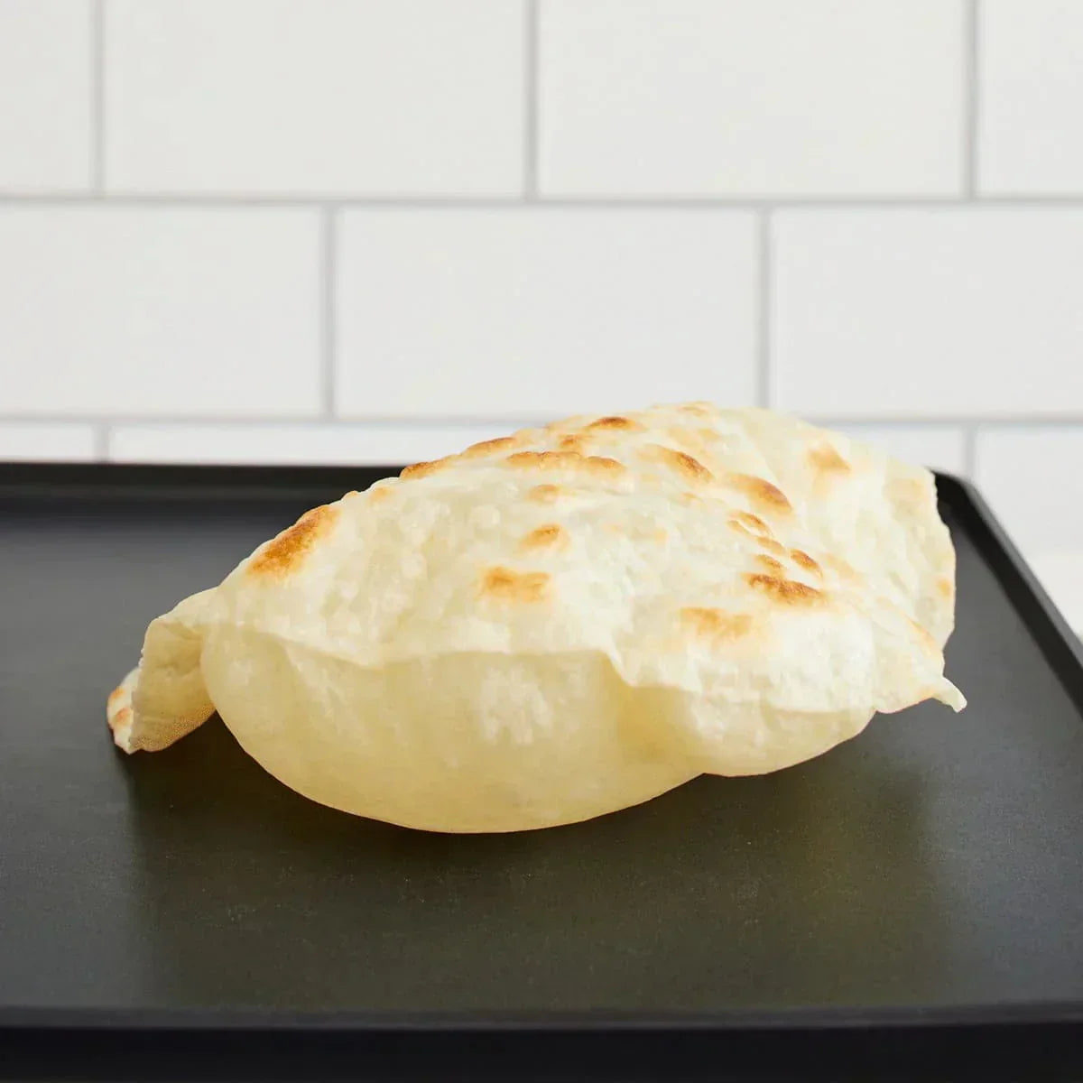 Fresh Rise & Puff tortilla puffing on a hot griddle with golden spots and soft, airy texture.