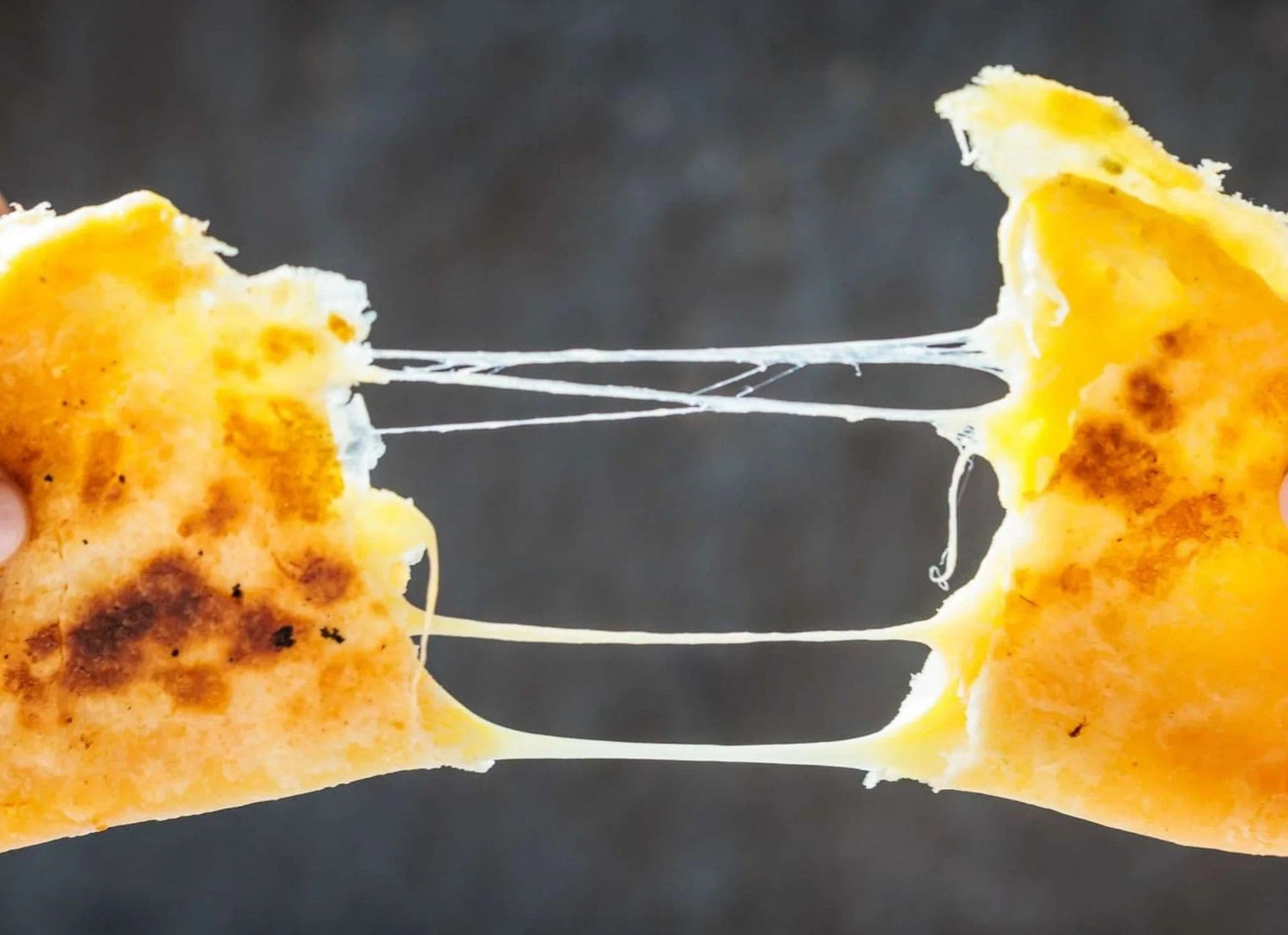 Hands pulling apart a cheesy flatbread with melted cheese stretch, made by Rise and Puff.