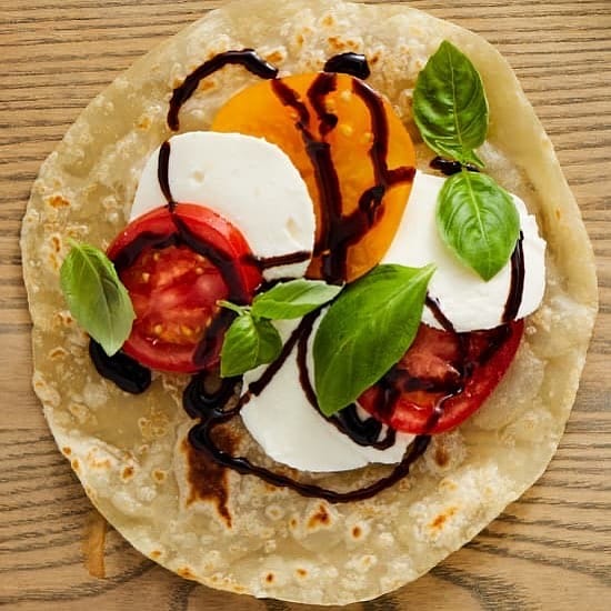 Fresh tortilla topped with tomatoes and herbs from Rise & Puff Gourmet Quesadillas & Tortillas.
