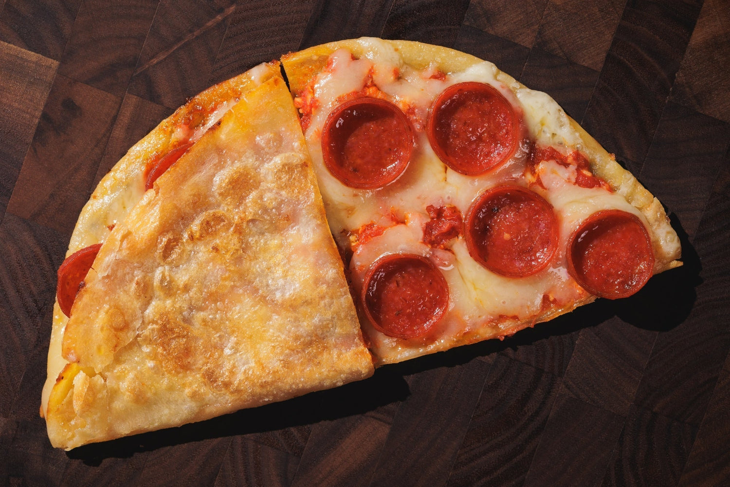 Rise and Puff tortillas, half-folded pepperoni pizza with melted cheese and golden crust on a wooden surface.
