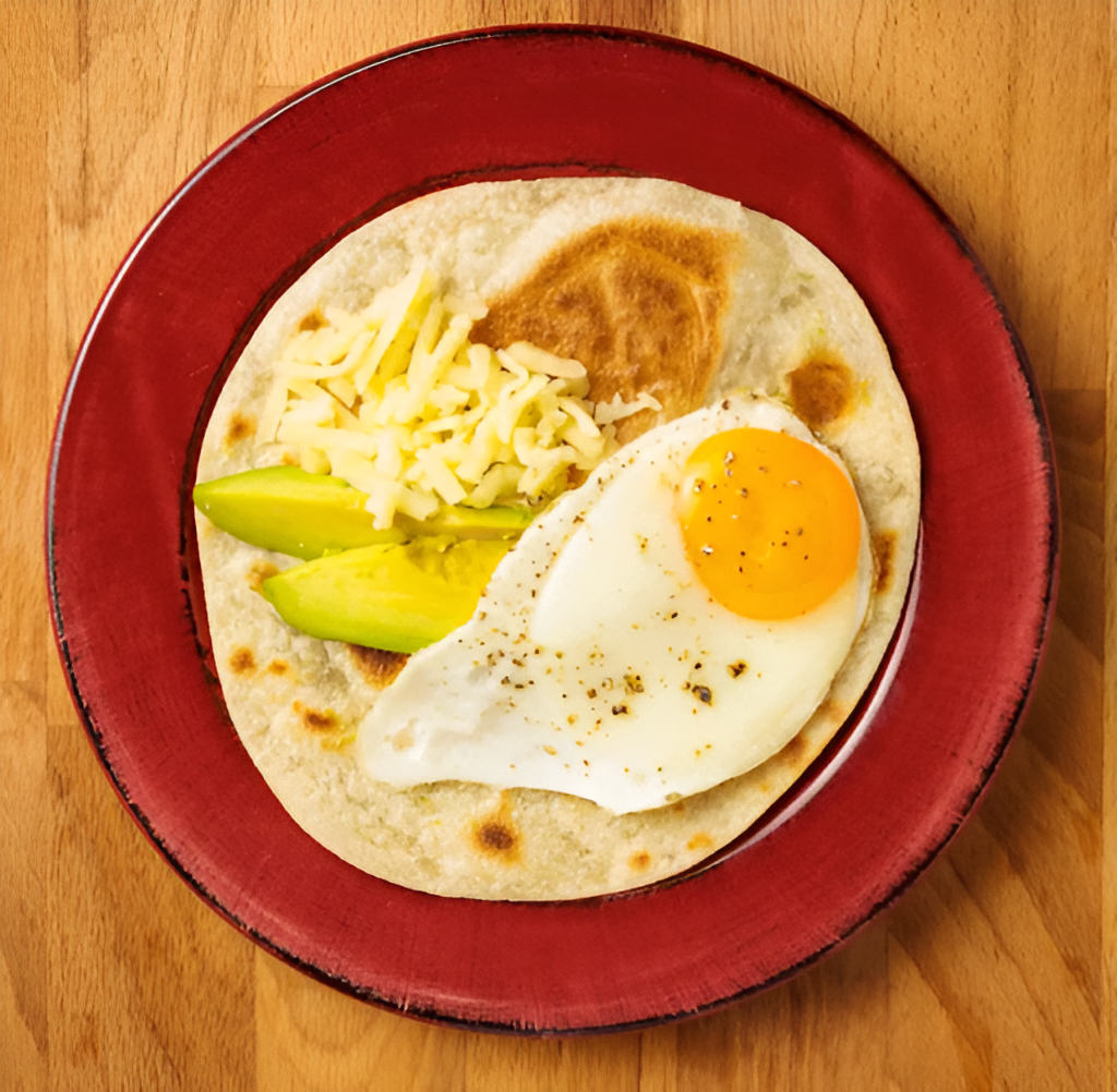 Picture of a breakfast wrap made with Rise & Puff’s tortilla, eggs, cheese, and avocado.