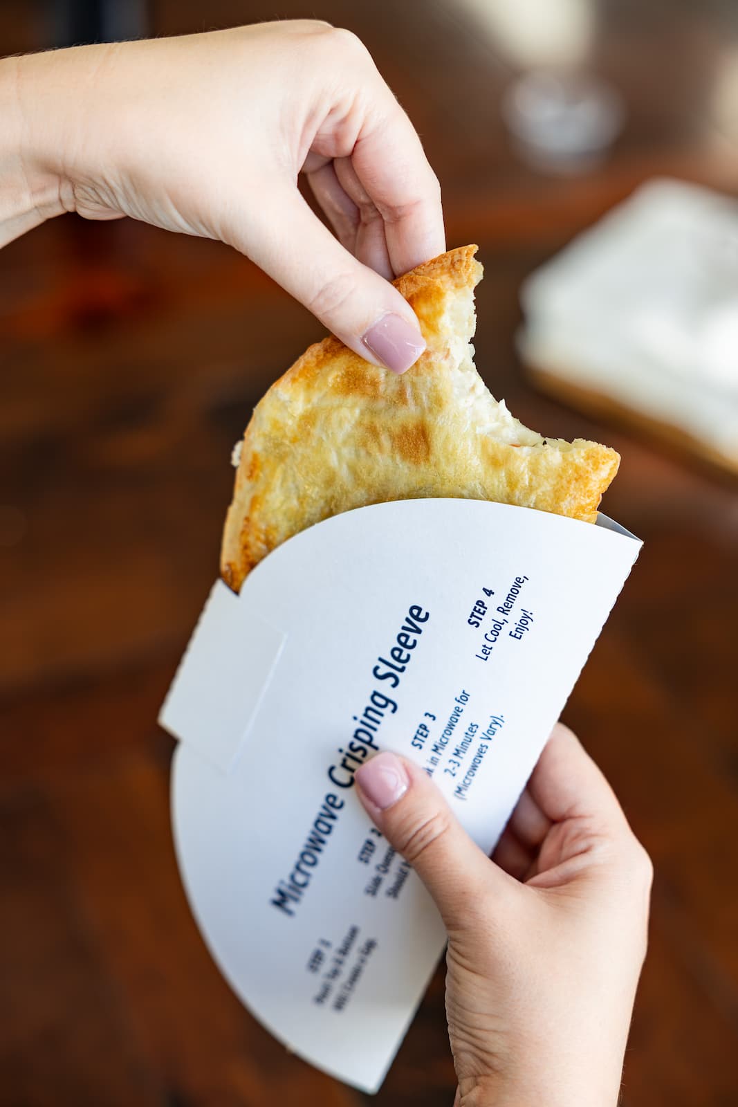 Person holding a chicken pot pie wrapped in a crisping sleeve for the microwave