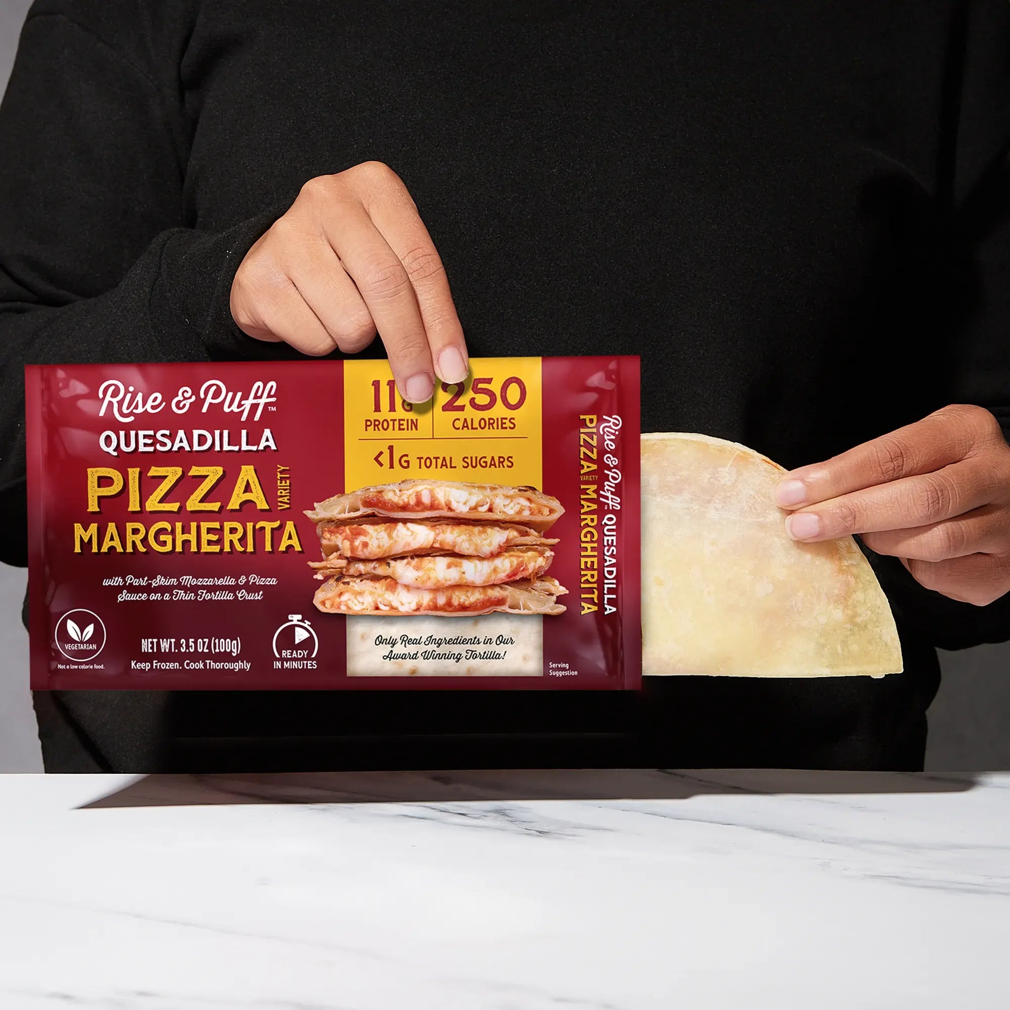 Rise & Puff Pizza Margherita Quesadilla shown coming out of its frozen retail packaging
