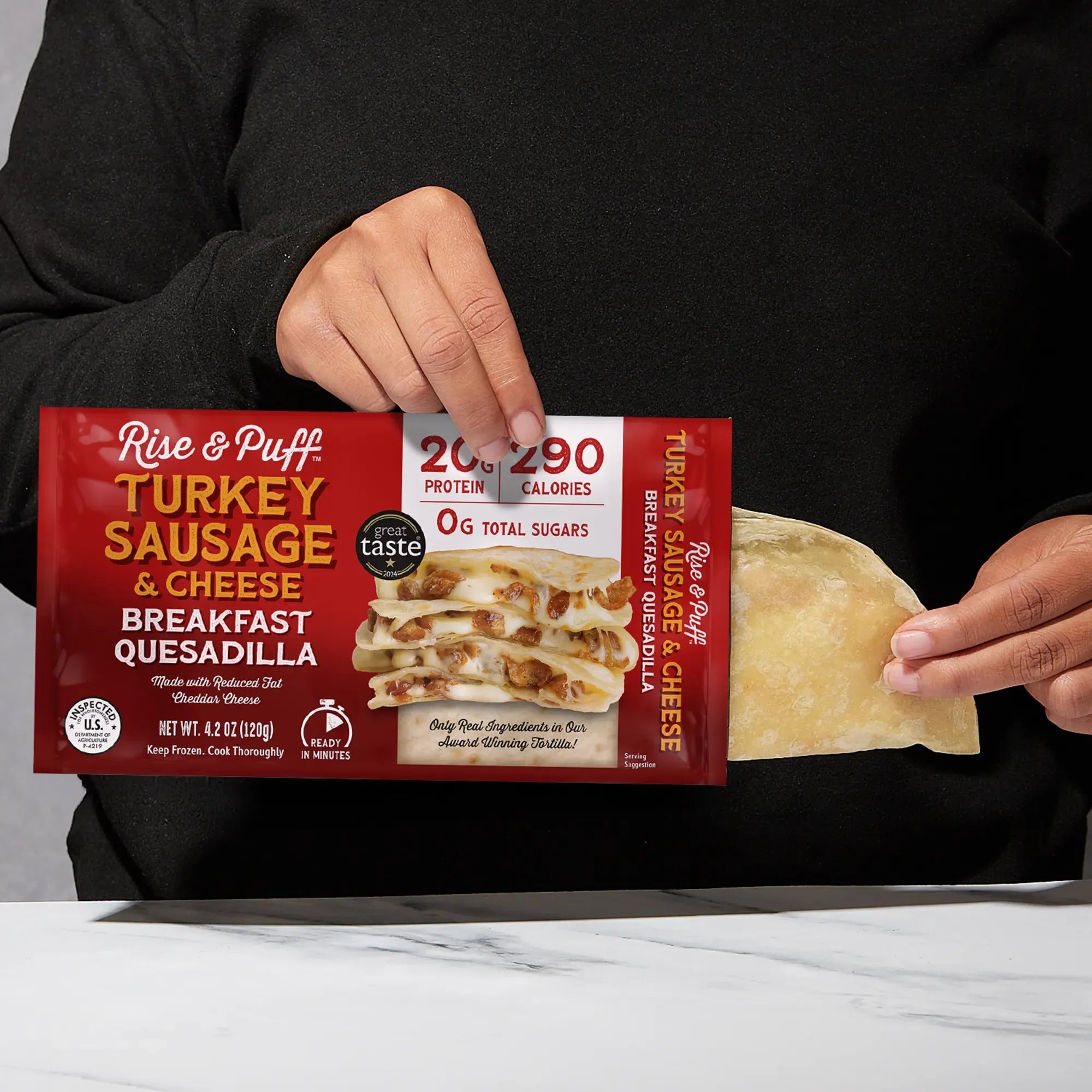 Rise & Puff Turkey Sausage & Cheese Breakfast Quesadilla shown coming out of its frozen retail packaging