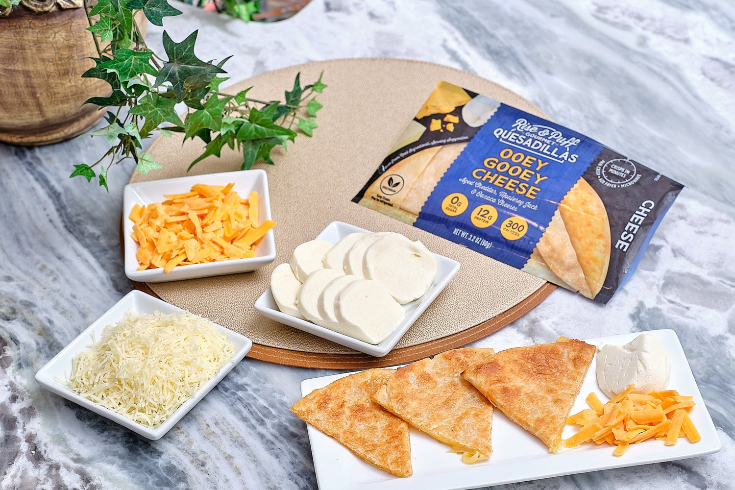Rise & Puff Ooey Gooey Cheese quesadilla served with assorted cheeses on a marble table for a fresh, melty meal. 