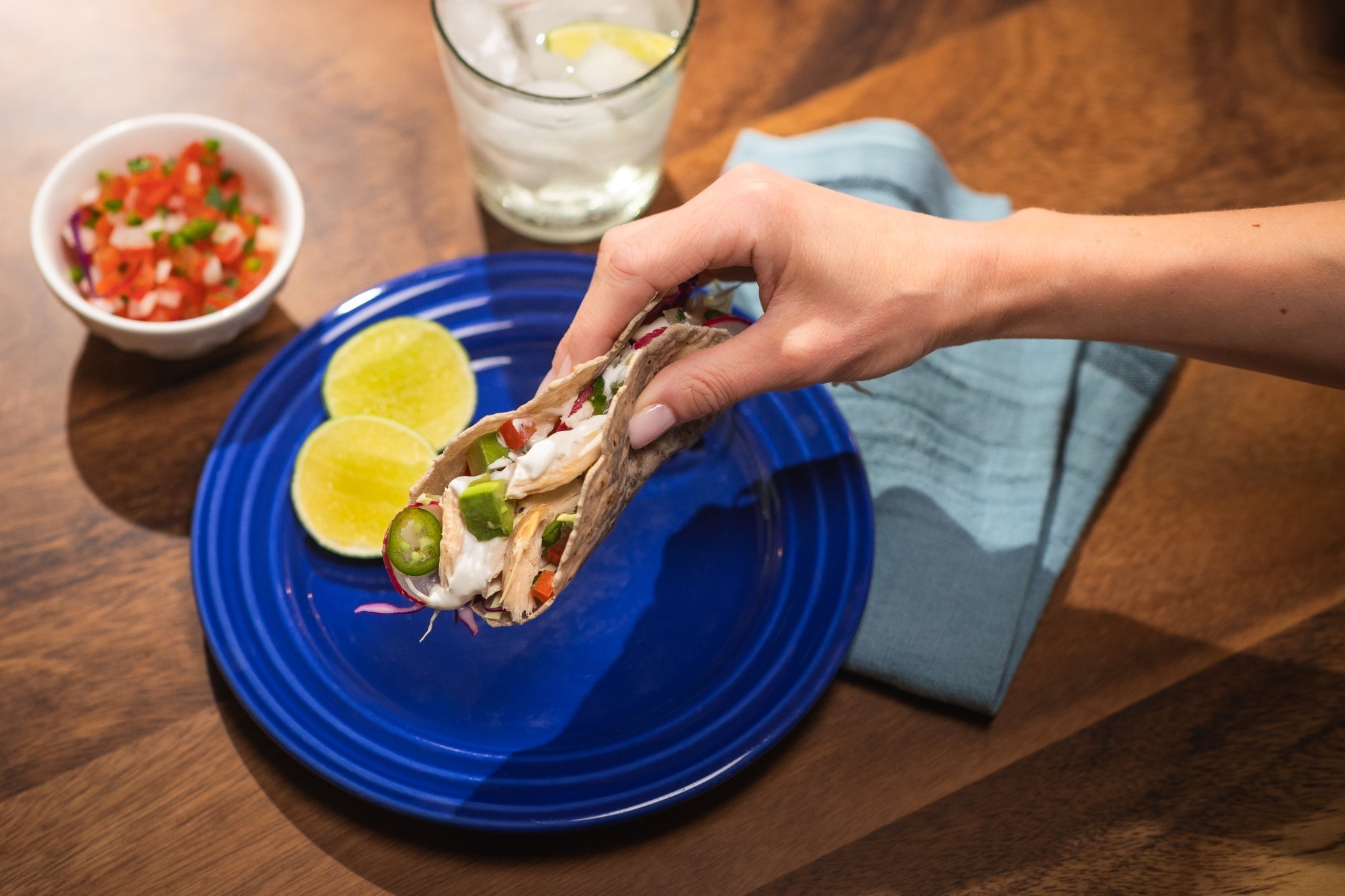 A taco made with Rise & Puff tortilla served on a plate with lime wedges and salsa.