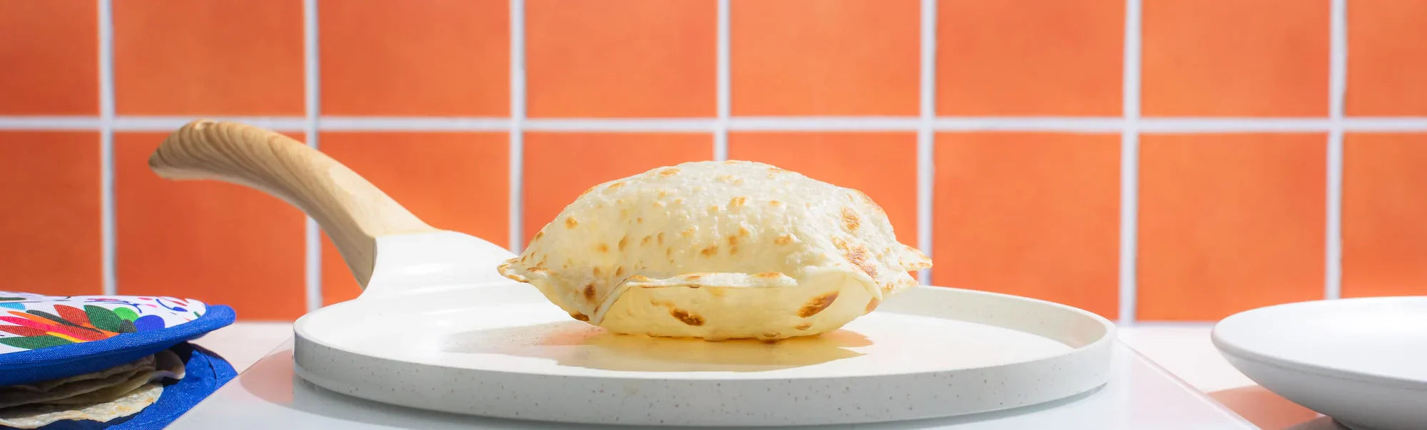 Rise & Puff puffy tortilla on a white plate with "Clean, Puffy Tortillas" text and orange tile background.