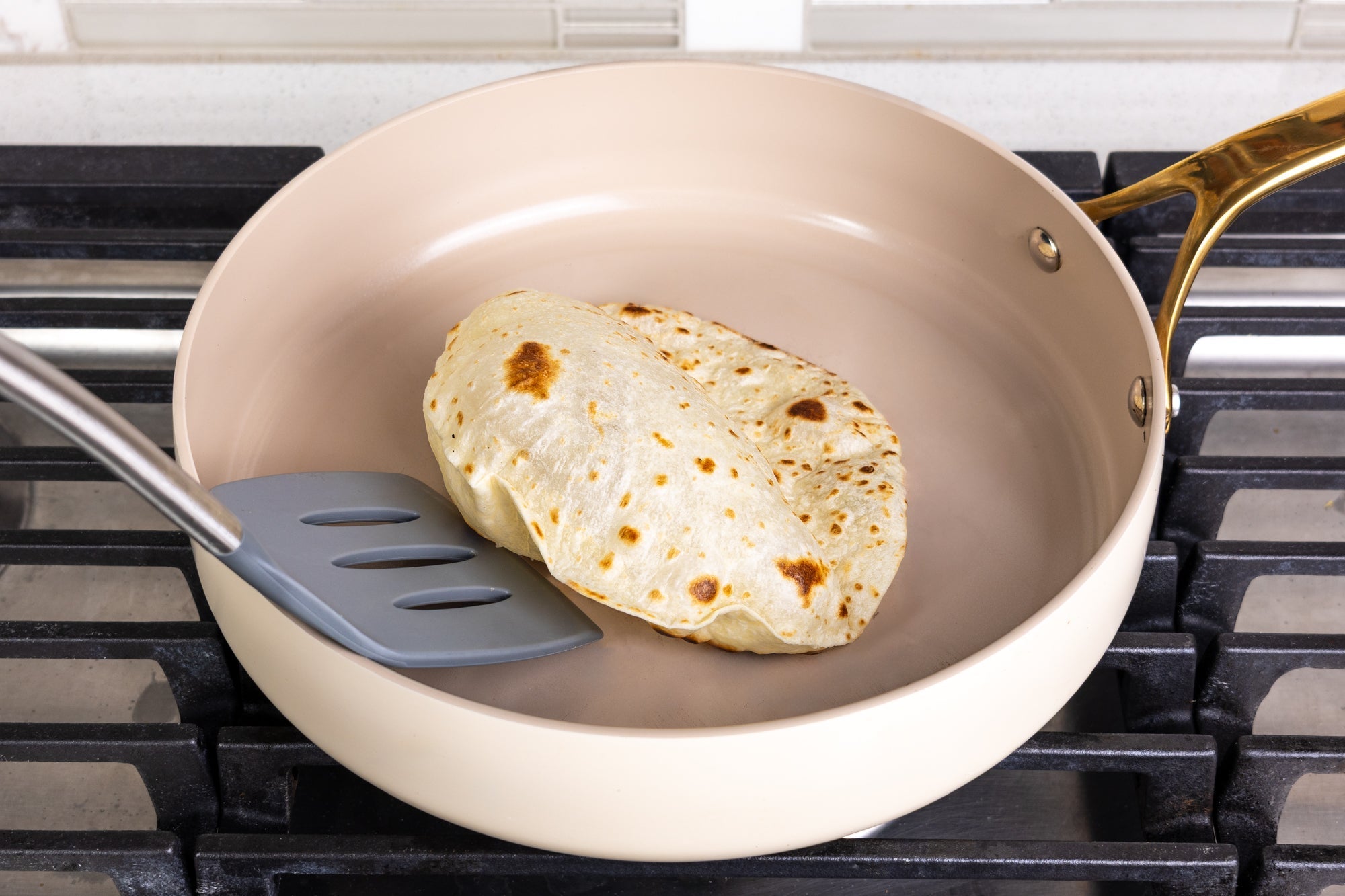  Rise & Puff tortilla puffing up in a beige pan on the stove, cooked to golden brown perfection.