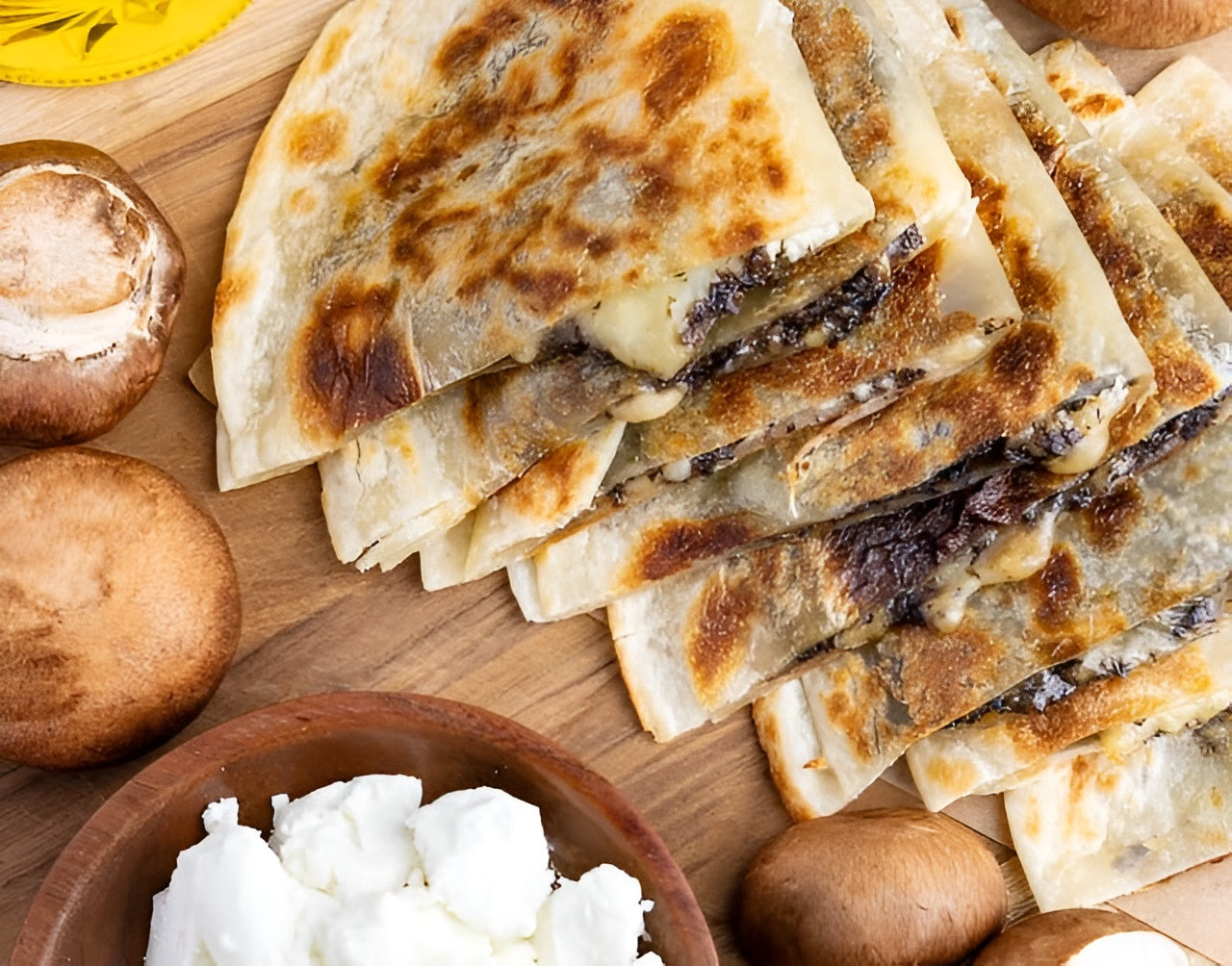 Rise and Puff mushroom and cheese quesadillas served on a wooden board with fresh ingredients.