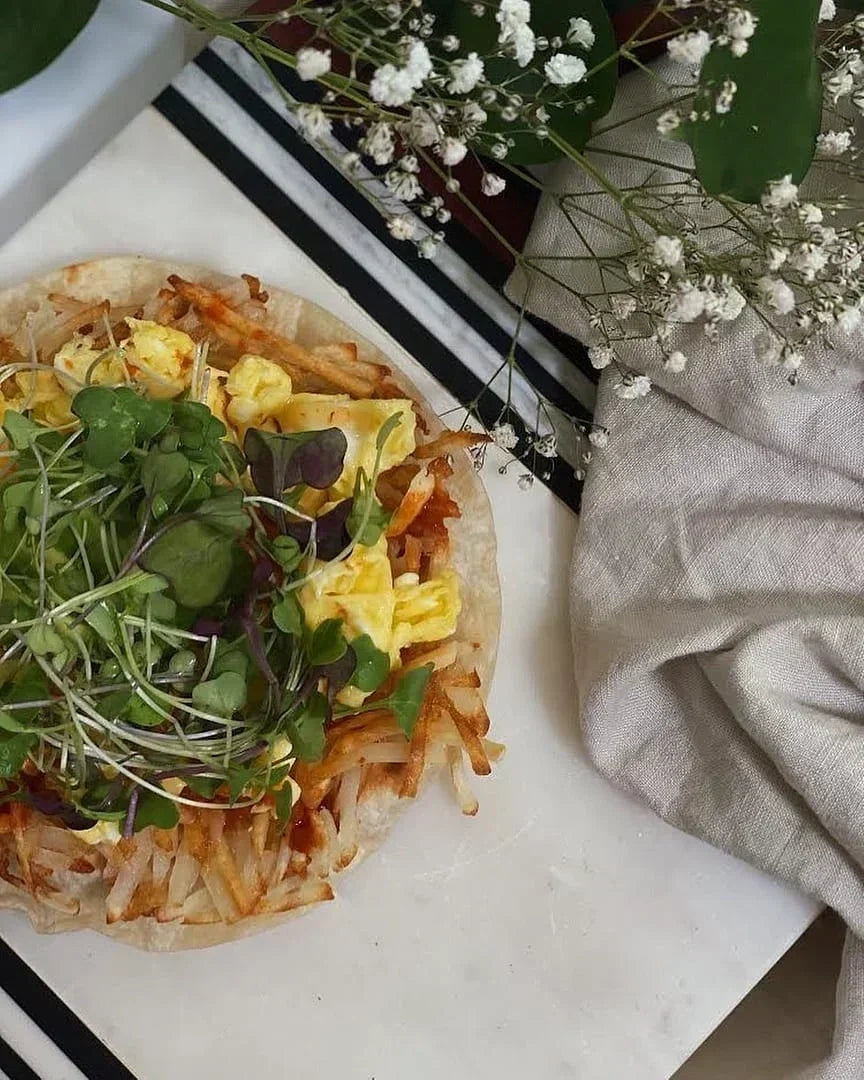 Fresh tortilla wrap filled with eggs, leafy greens, tomatoes, and colorful vegetables on a wooden serving board.