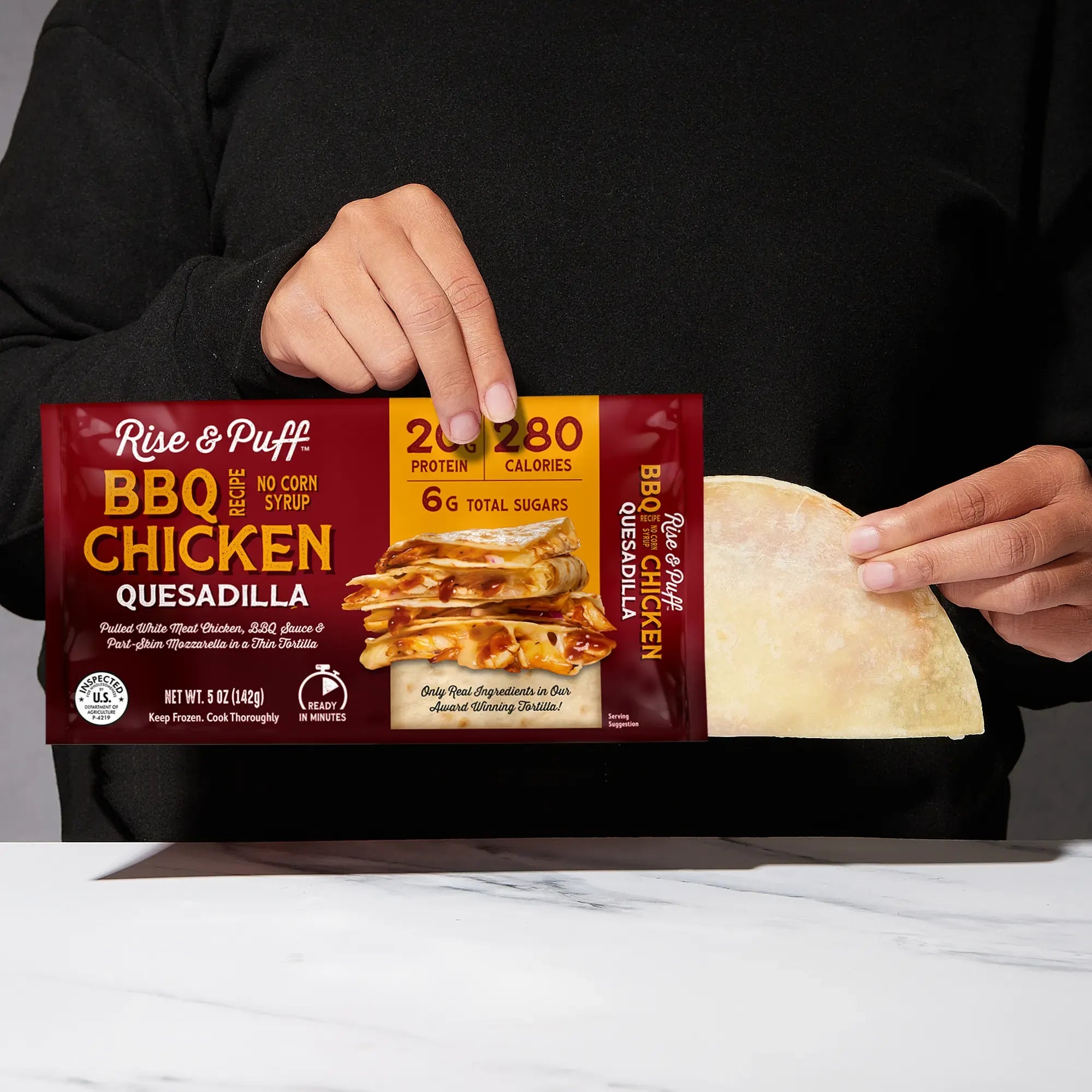 Rise & Puff BBQ Chicken Quesadilla shown coming out of its frozen retail packaging