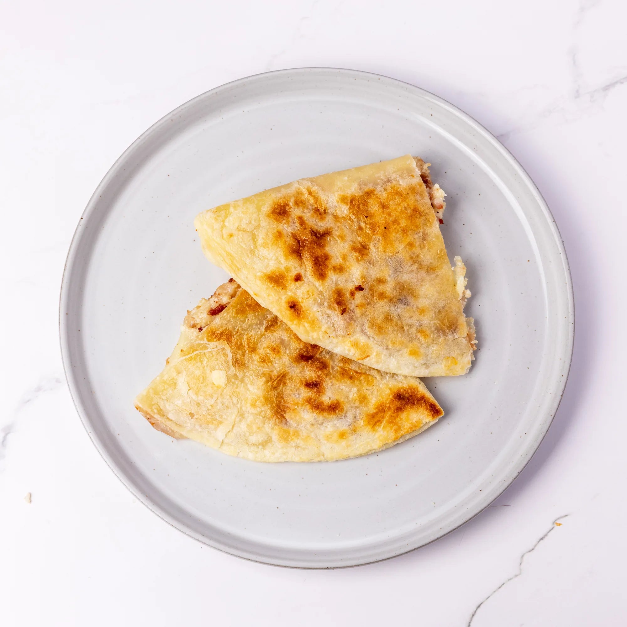 Bacon Egg & Cheese quesadilla on a white plate with a white background