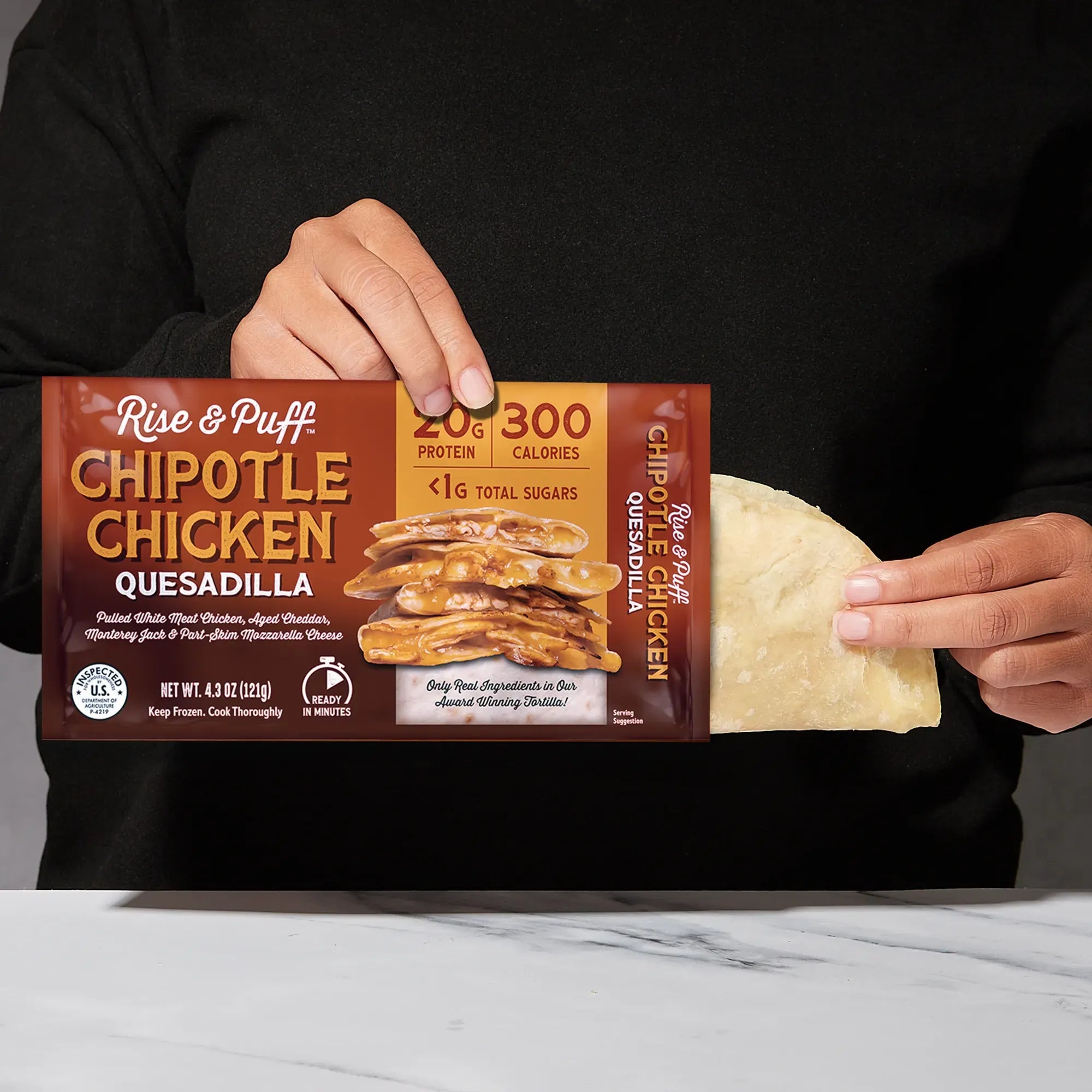 Rise & Puff Chipotle Chicken Quesadilla shown coming out of its frozen retail packaging