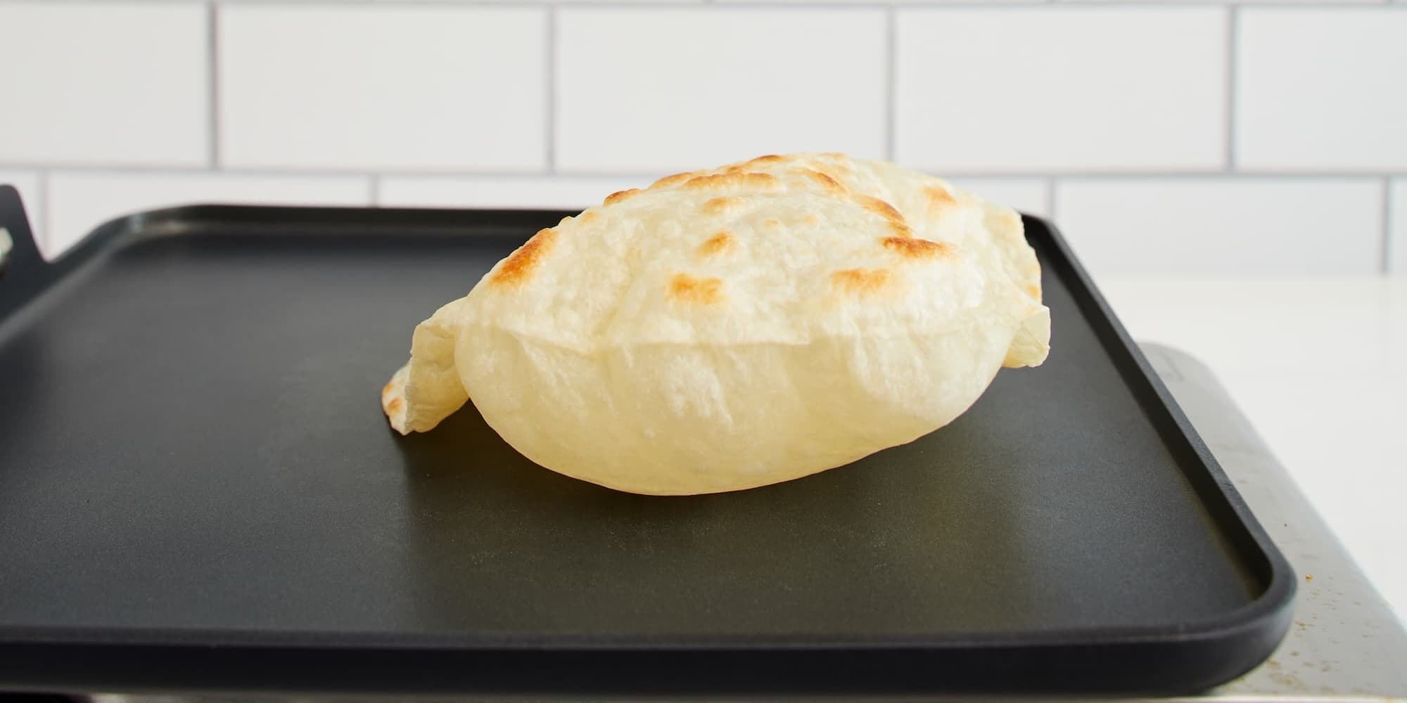 Tortilla on black griddle after 60 seconds puffed up